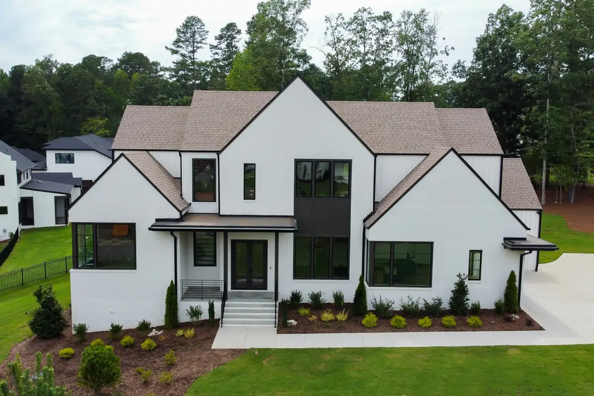 White two-story house with a tan shingle roof, black window frames and a black double front door