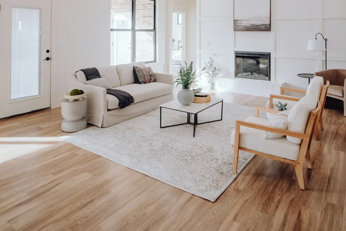 Bright living room with white board-and-batten walls, an electric fireplace, a cream sofa and wood armchairs